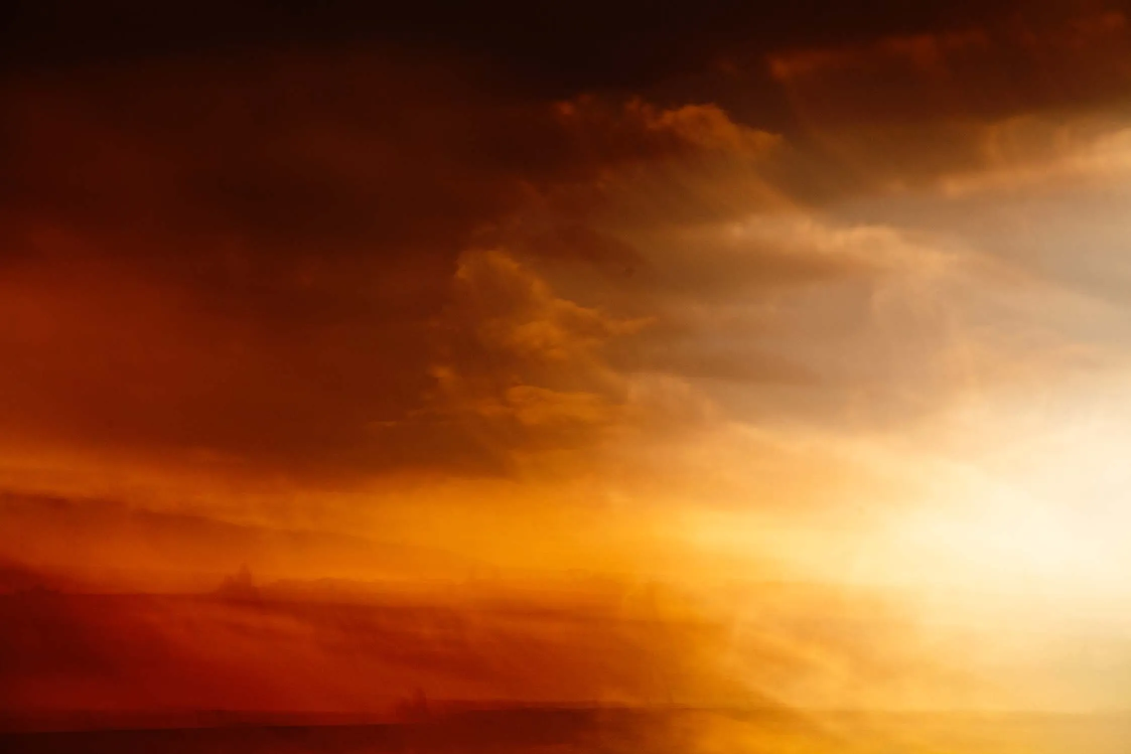 Cielo drammatico arancione al tramonto con nuvole scure.