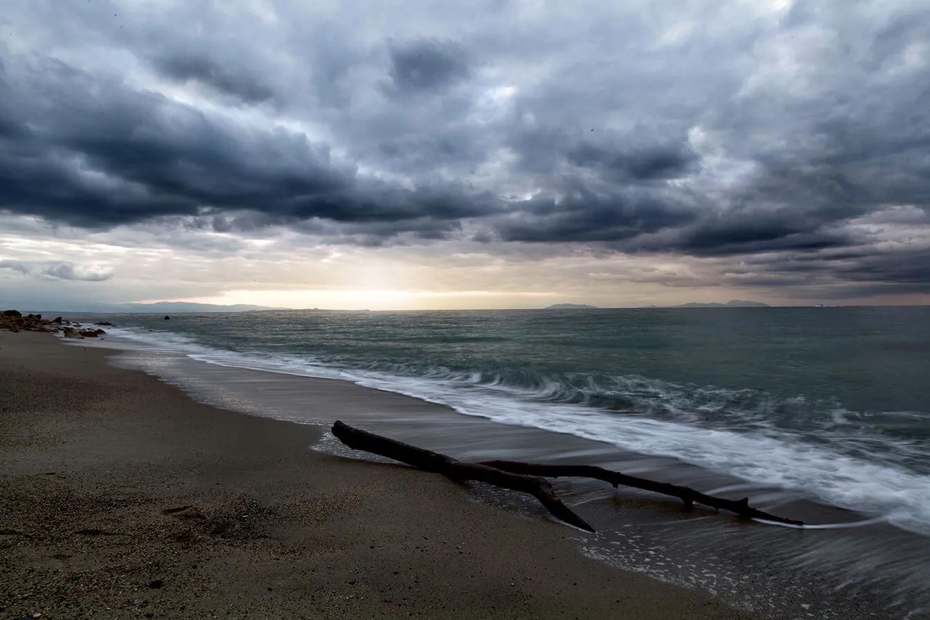 Cielo nuvoloso e tempestoso sul mare, un ramo sulla battigia.