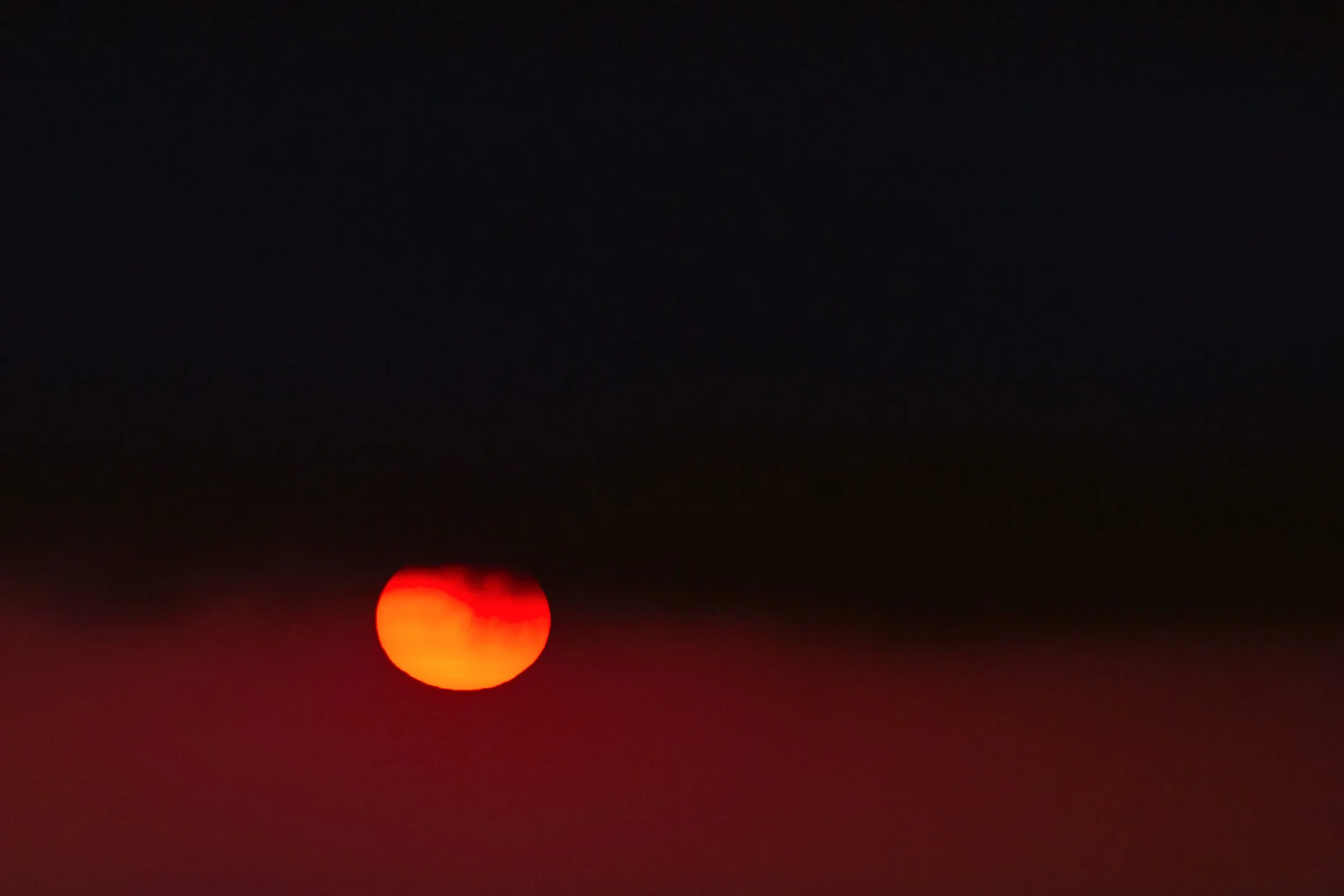 Piccolo sole rosso-arancio in un cielo quasi nero.