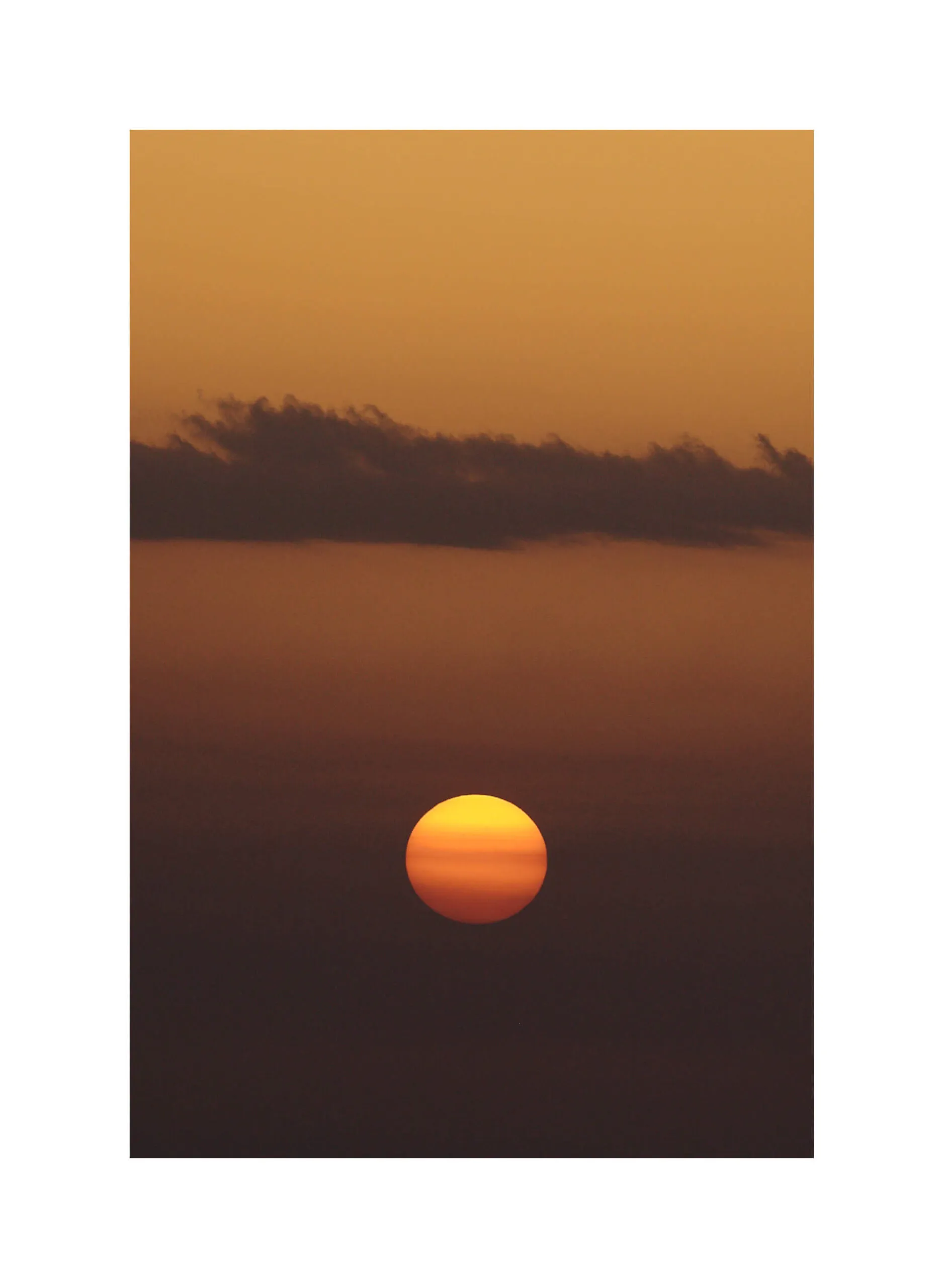 Tramonto verticale, sole parzialmente coperto da una nuvola.
